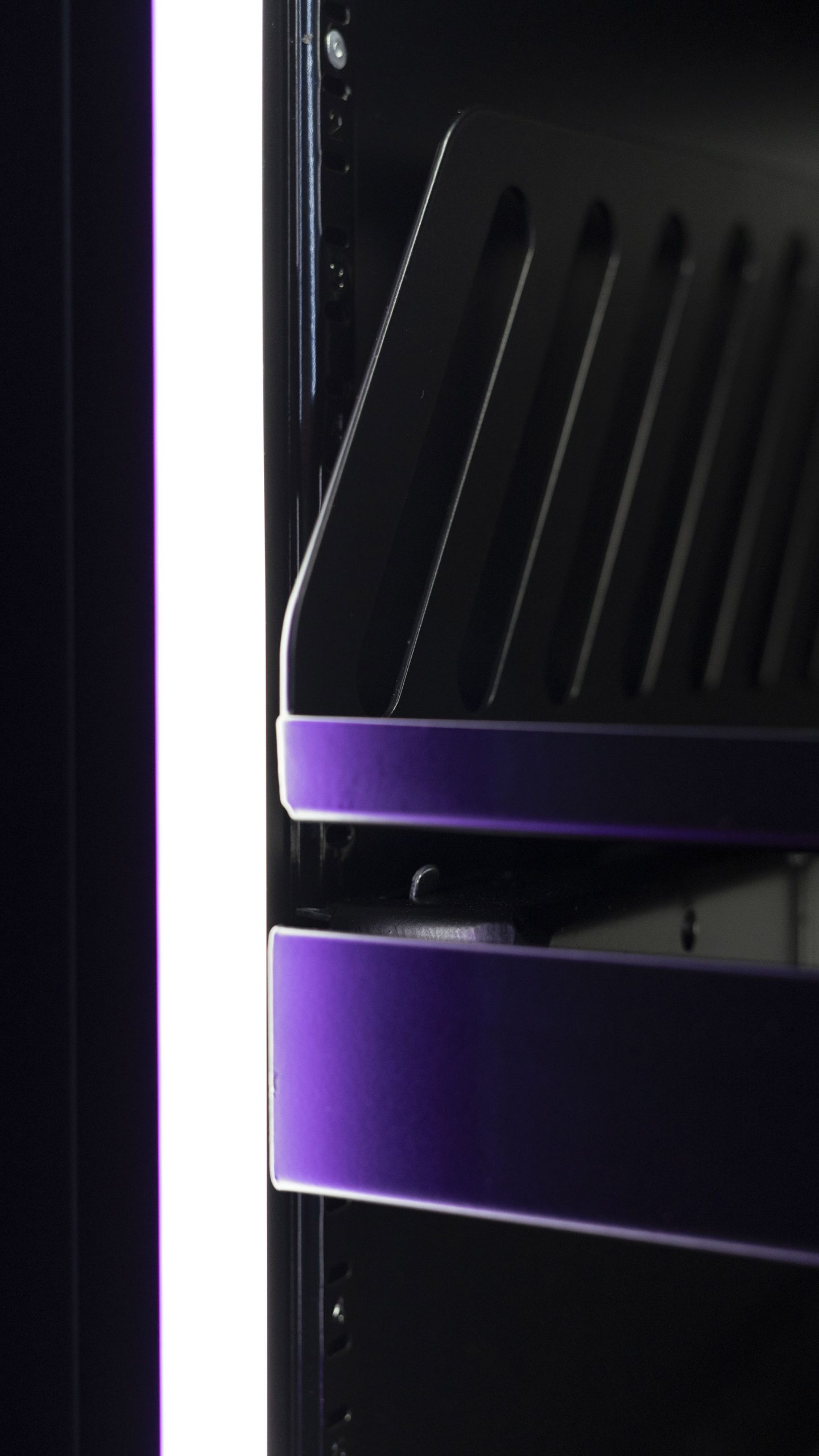 Front edges of two shelves inside a cabinet under dim lighting
