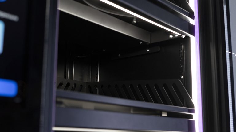 Empty shelf with a slotted front edge inside a cabinet, LED lighting above
