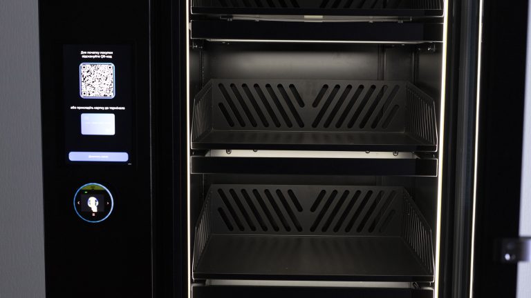 Front panel to the left of the cabinet door with a screen, a QR code and a card reader, empty basket shelves alongside