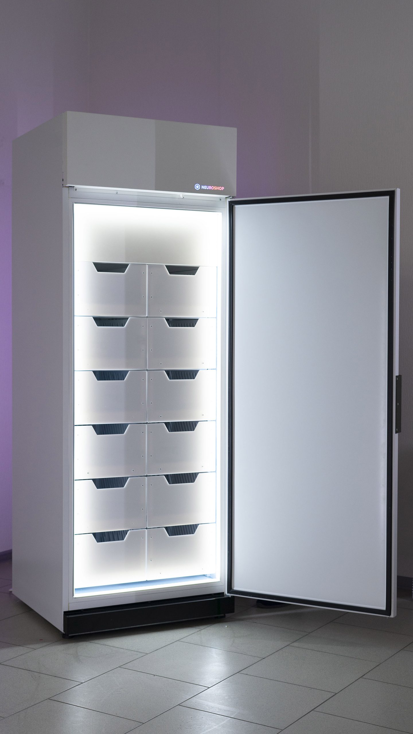 White cabinet with its solid door open, six tiers of empty white trays inside
