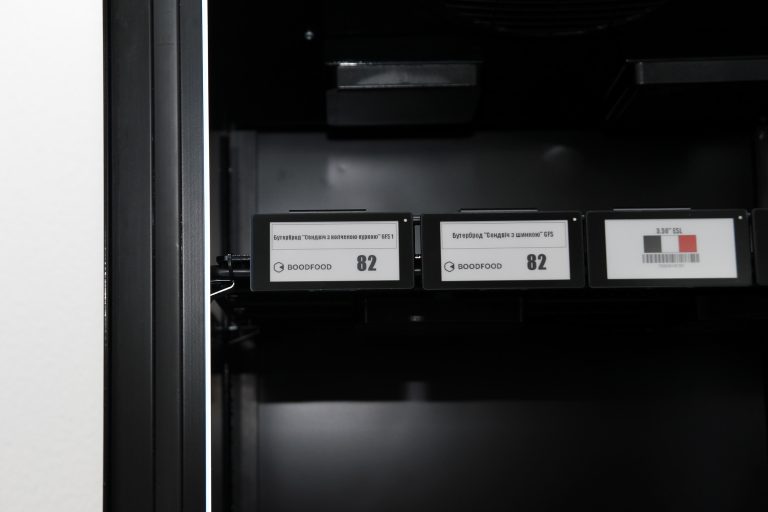 Electronic shelf labels on the front edge of an empty shelf inside a cabinet