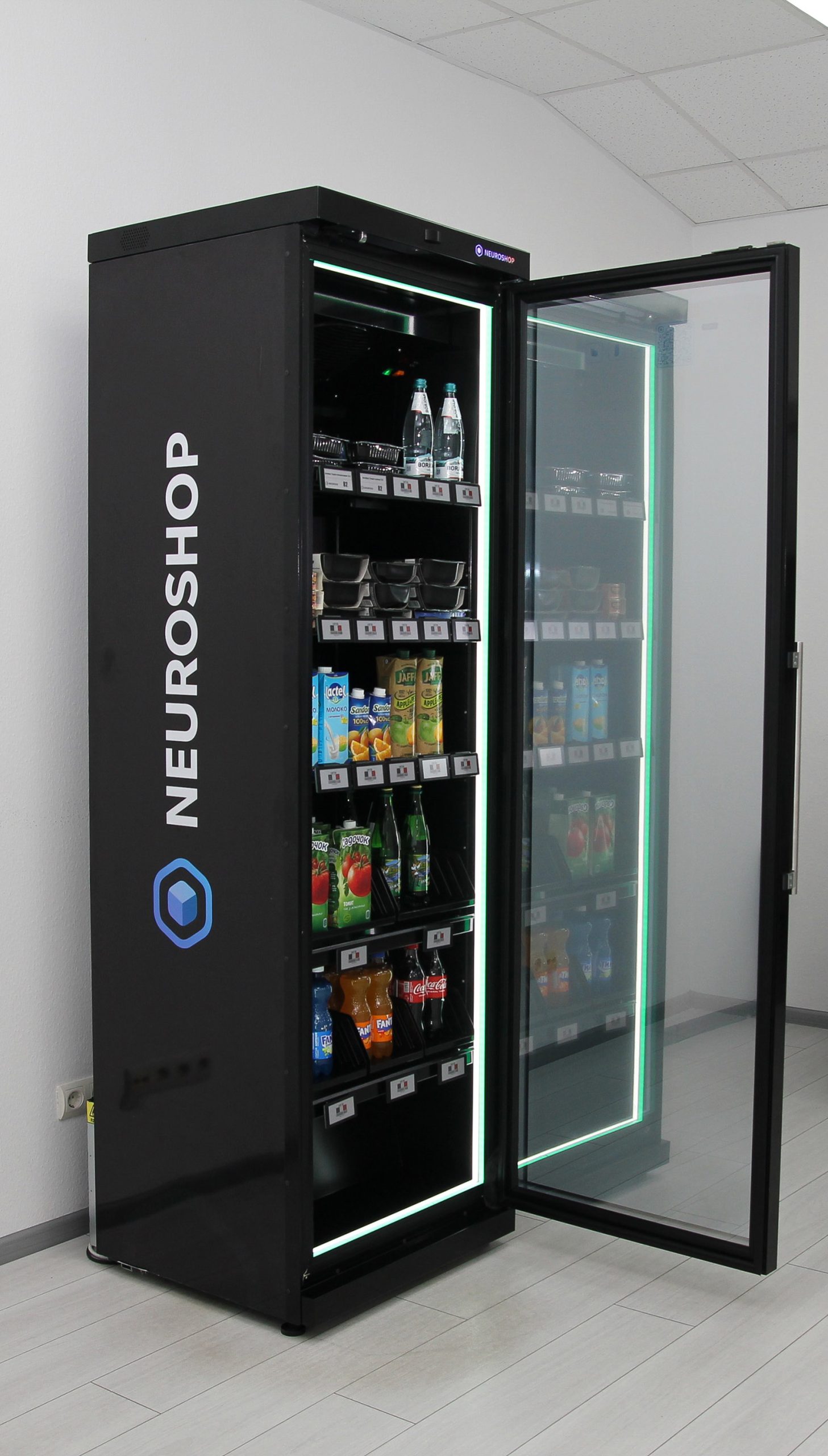 Open lit Neuroshop cabinet, bottled water, prepared salads and juice on shelves edged with electronic shelf labels