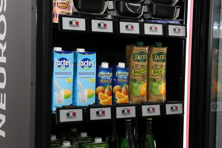 Shelves of an open cabinet with milk and juice cartons, electronic shelf labels along the shelf edges