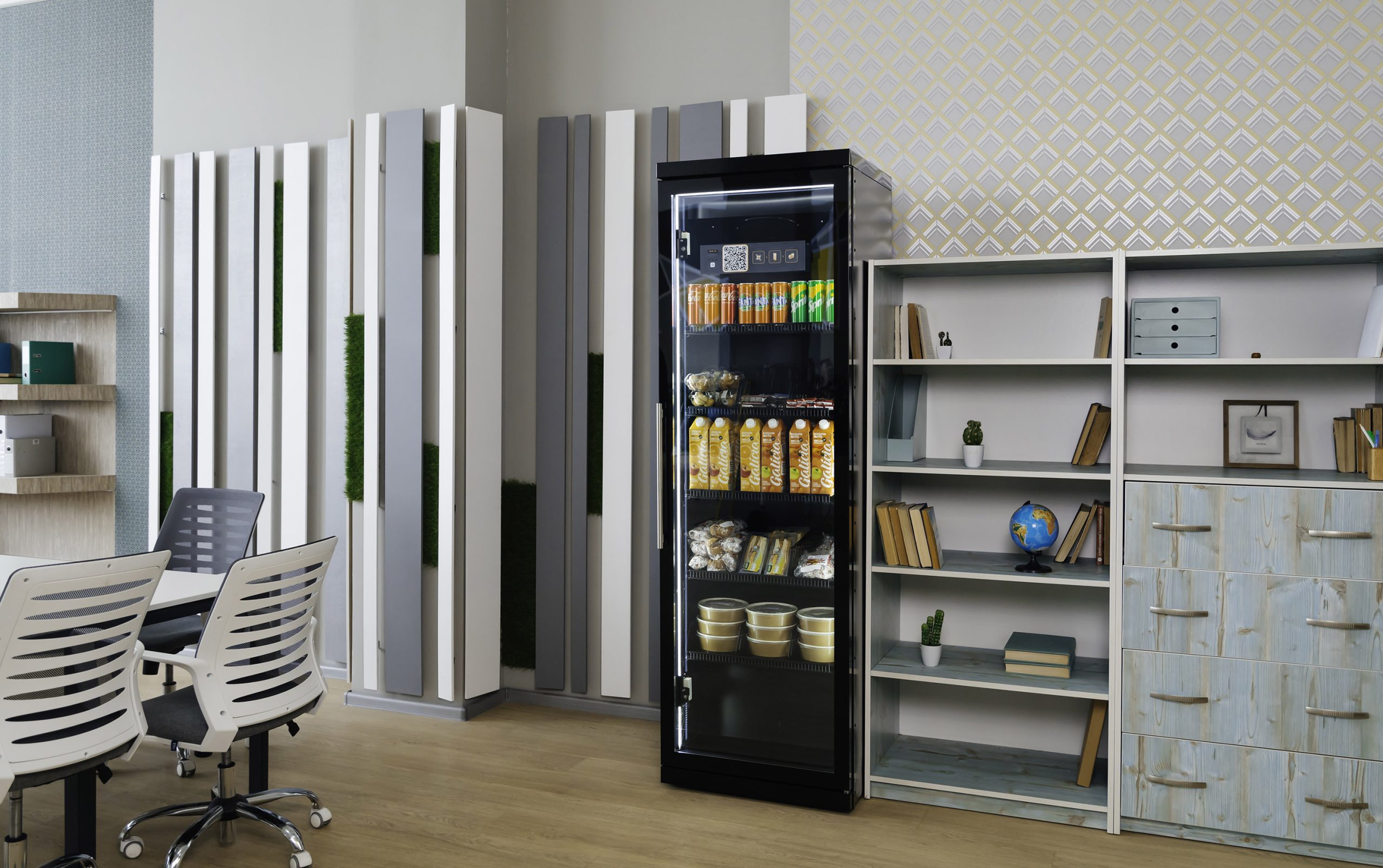 Black cabinet with a glass door in an office with desks and chairs, juice, snacks and cups on the shelves