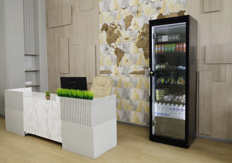 Black cabinet with a glass door by a reception desk, drinks and packaged food on the shelves